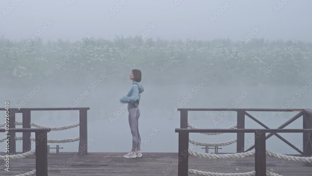 Young fit woman doing sport and meditating on the nature close to foggy lake Young fit woman doing sport and meditating on the nature close to foggy lake