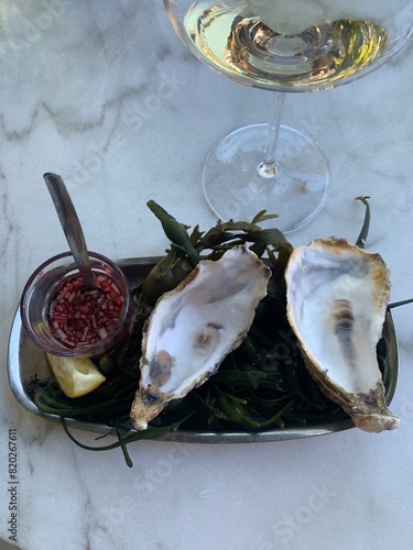 Foto Oysters shells on oval tray with white whine glass