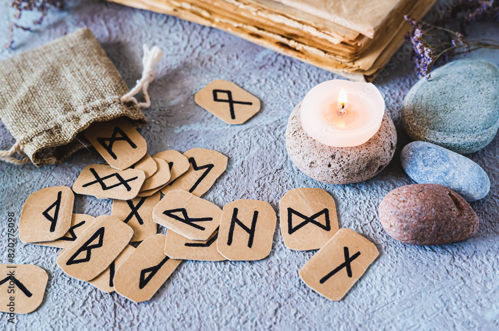 Scandinavian ancient runes for fortune telling, a bag, a candle and stones on the table Scandinavian ancient runes for fortune telling, a bag, a candle and stones on the table