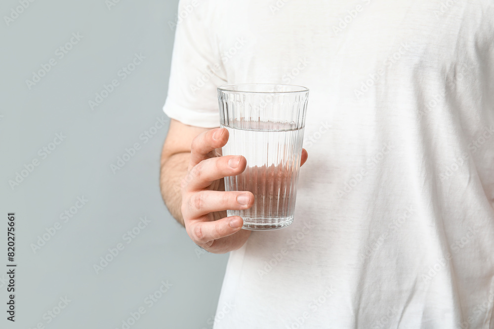 Young man with glass of clean water on grey background Young man with glass of clean water on grey background