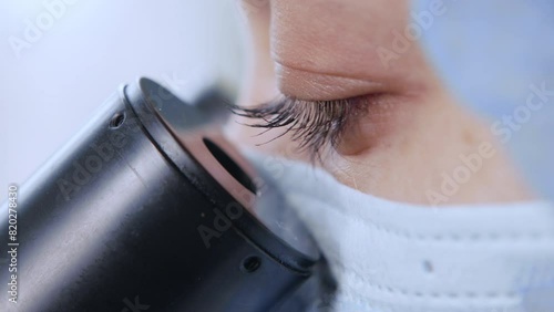 Female scientist looking microscope eyepiece in laboratory, close up