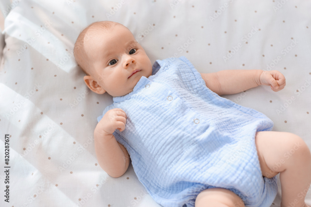 Cute little baby lying in crib at home, top view Cute little baby lying in crib at home, top view