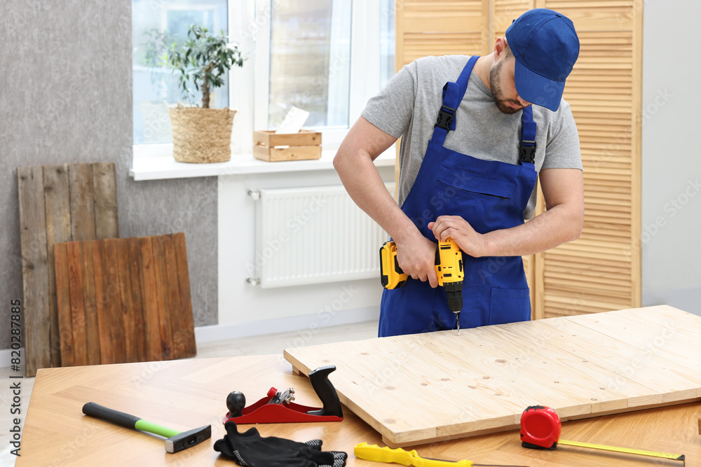 Young worker using electric drill at table in workshop Young worker using electric drill at table in workshop