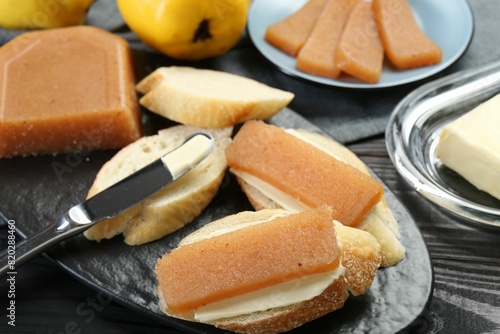 Tasty sandwiches with quince paste served on black wooden table, closeup photo