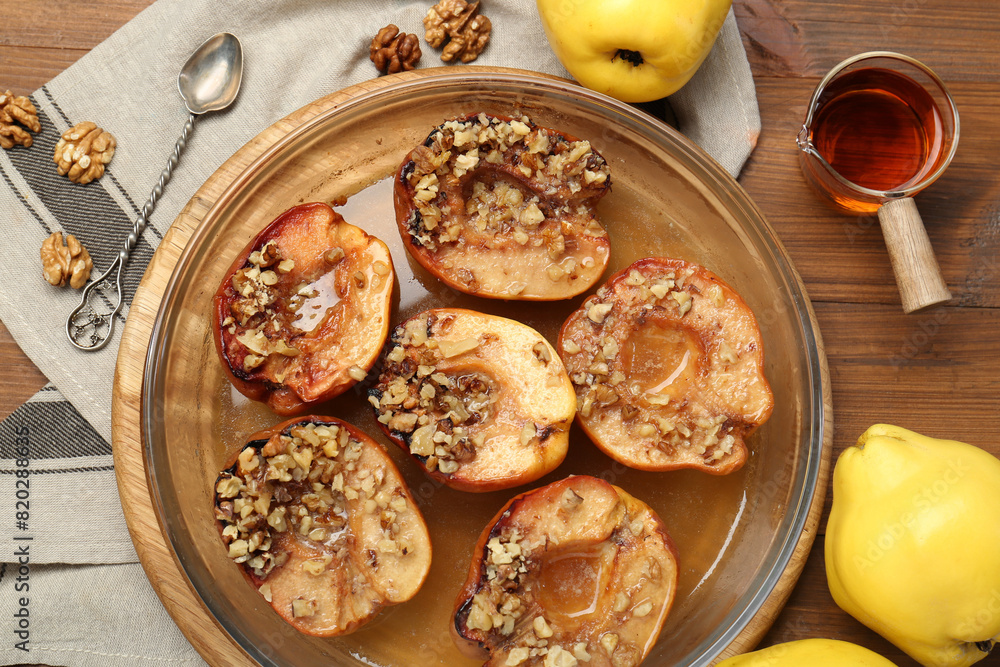 Tasty baked quinces with walnuts and honey in bowl on wooden table, flat lay Tasty baked quinces with walnuts and honey in bowl on wooden table, flat lay