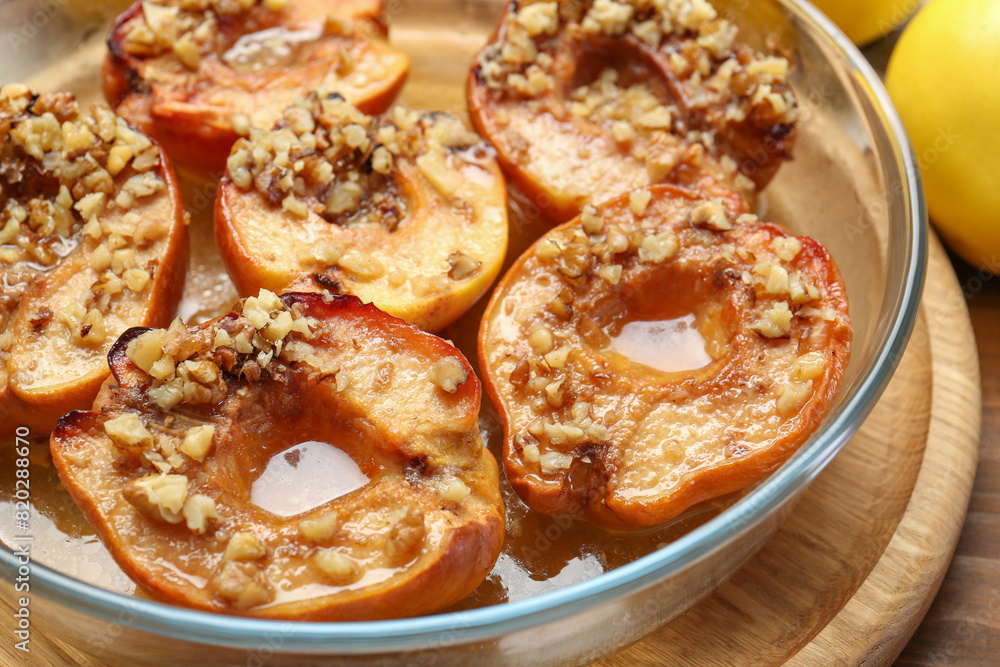 Tasty baked quinces with walnuts and honey in bowl on wooden table, closeup Tasty baked quinces with walnuts and honey in bowl on wooden table, closeup
