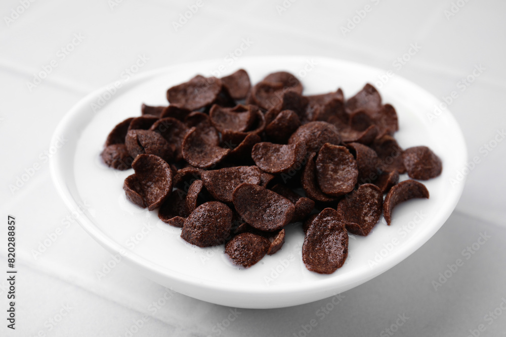 Breakfast cereal. Chocolate corn flakes and milk in bowl on white tiled table, closeup Breakfast cereal. Chocolate corn flakes and milk in bowl on white tiled table, closeup