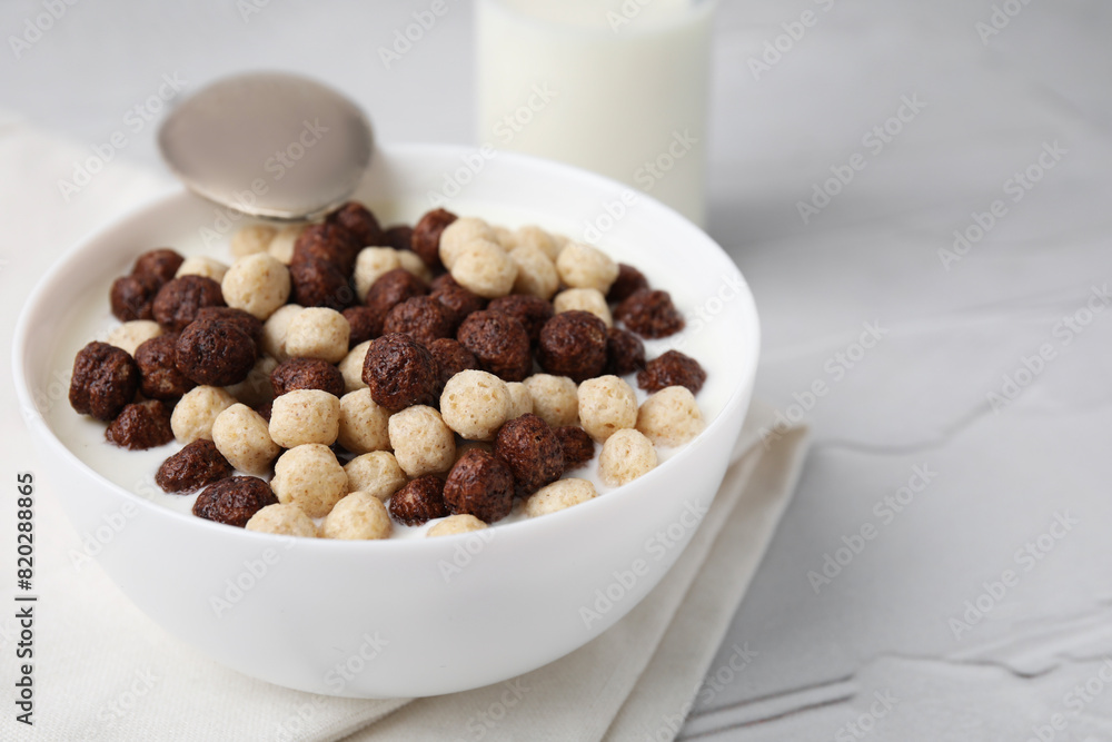 Breakfast cereal. Tasty corn balls with milk in bowl and spoon on white textured table, closeup. Space for text Breakfast cereal. Tasty corn balls with milk in bowl and spoon on white textured table, closeup. Space for text