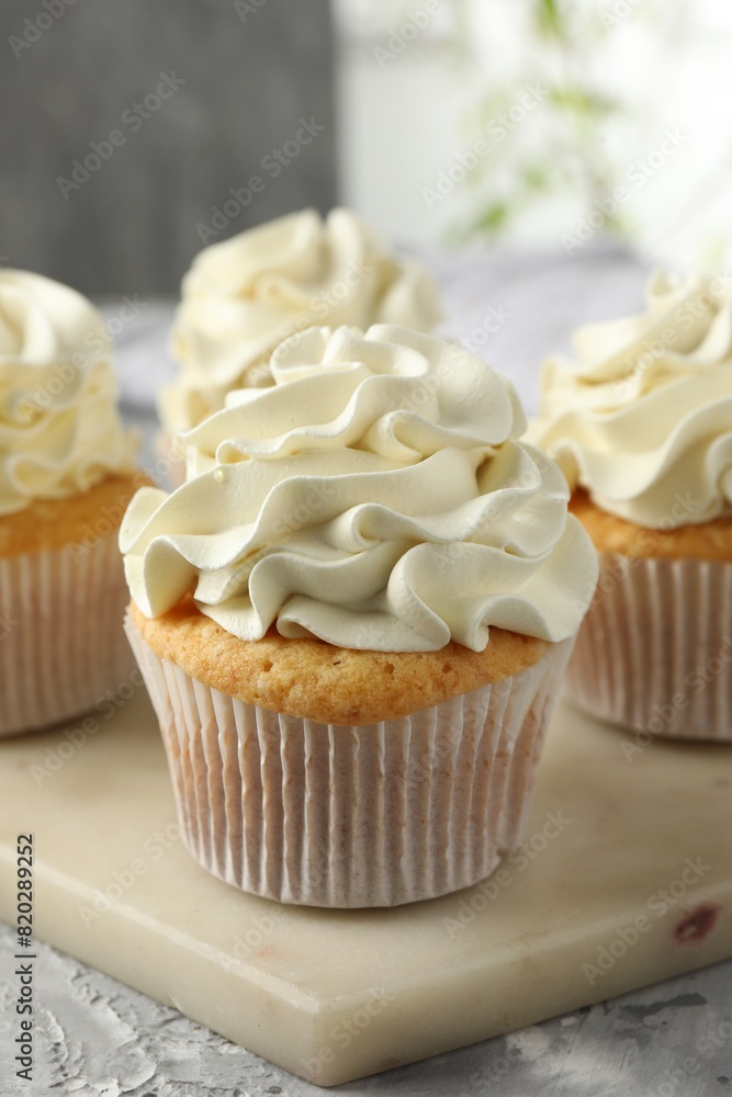 Tasty cupcakes with vanilla cream on grey table, closeup Tasty cupcakes with vanilla cream on grey table, closeup