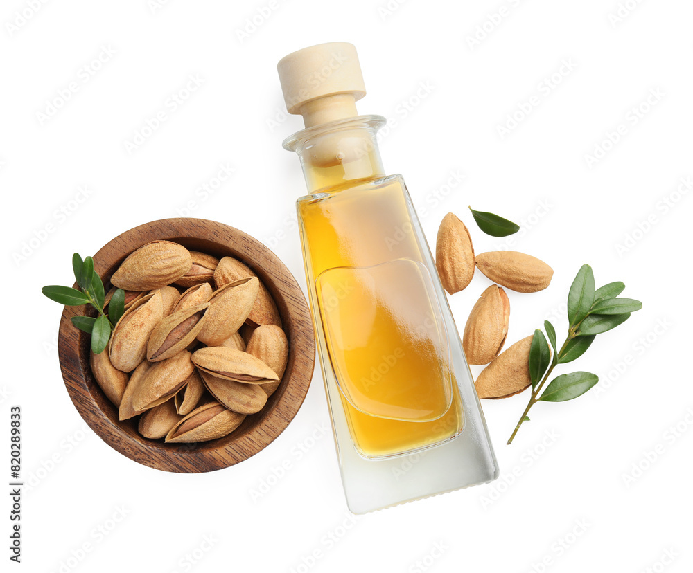 Bottle of almond oil and fresh nuts in bowl isolated on white, top view Bottle of almond oil and fresh nuts in bowl isolated on white, top view