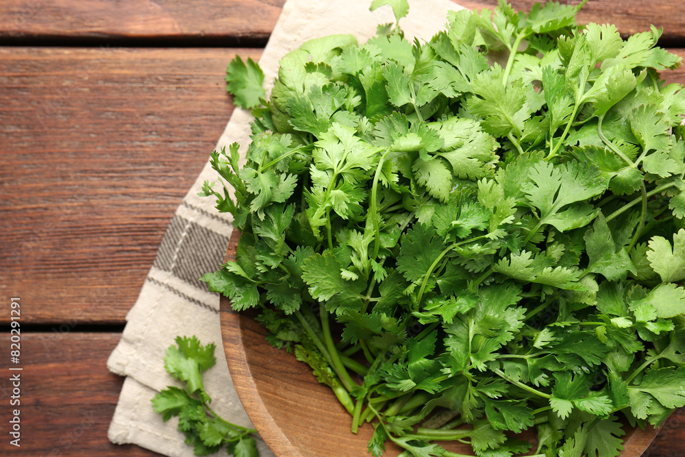 Fresh coriander in bowl on wooden table, top view Fresh coriander in bowl on wooden table, top view