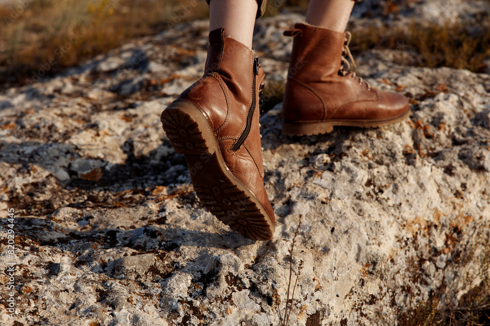 Adventure in the field a person wearing brown boots standing on top of a rock in nature Adventure in the field a person wearing brown boots standing on top of a rock in nature