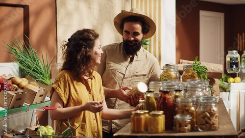 Portrait of happy couple in zero waste supermarket using shopping basket to purchase bulk items in nonpolluting glass containers. Smiling clients in local grocery shop buying organic pantry staples