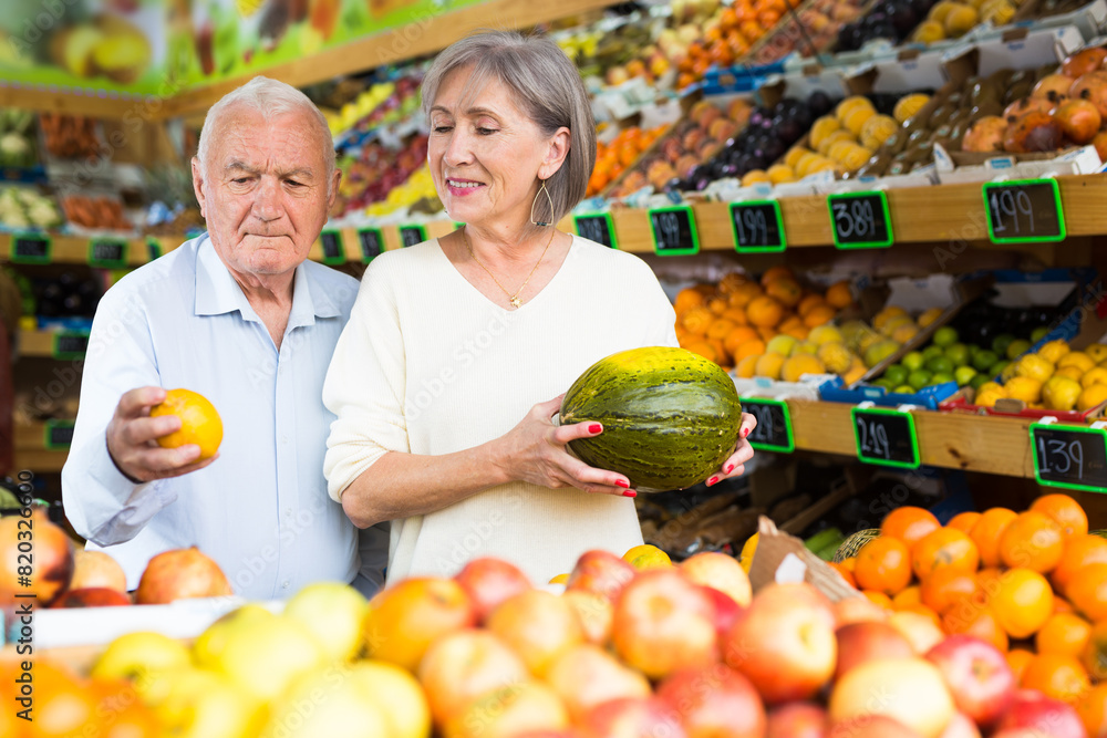Adult couple choosing fresh fruits and vegetables on the supermarket