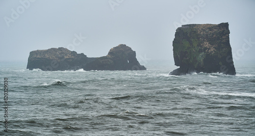 View of the sea with waves breaking on large basalt rocks in Iceland