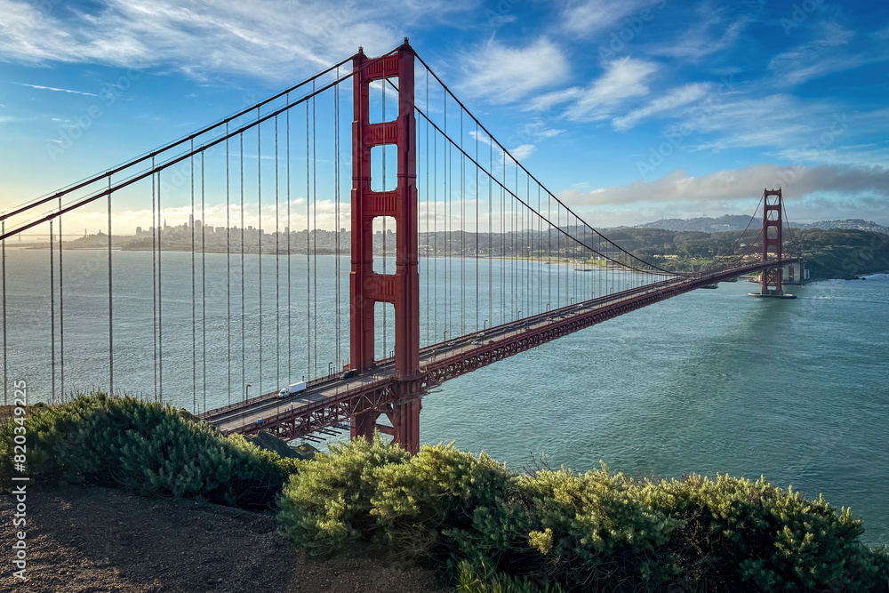 Fototapeta premium Scenic view of Golden Gate Bridge and cityscape of San Francisco, California, USA at sunrise against blue sky with clouds