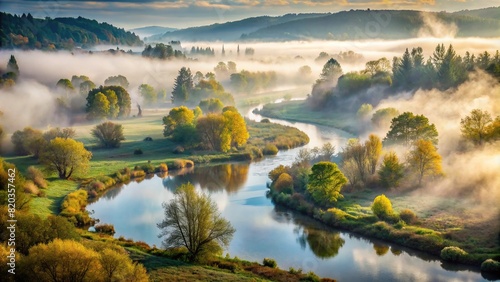 A misty morning scene of a tranquil river winding through a fog-covered valley, with trees emerging from the mist #820357462