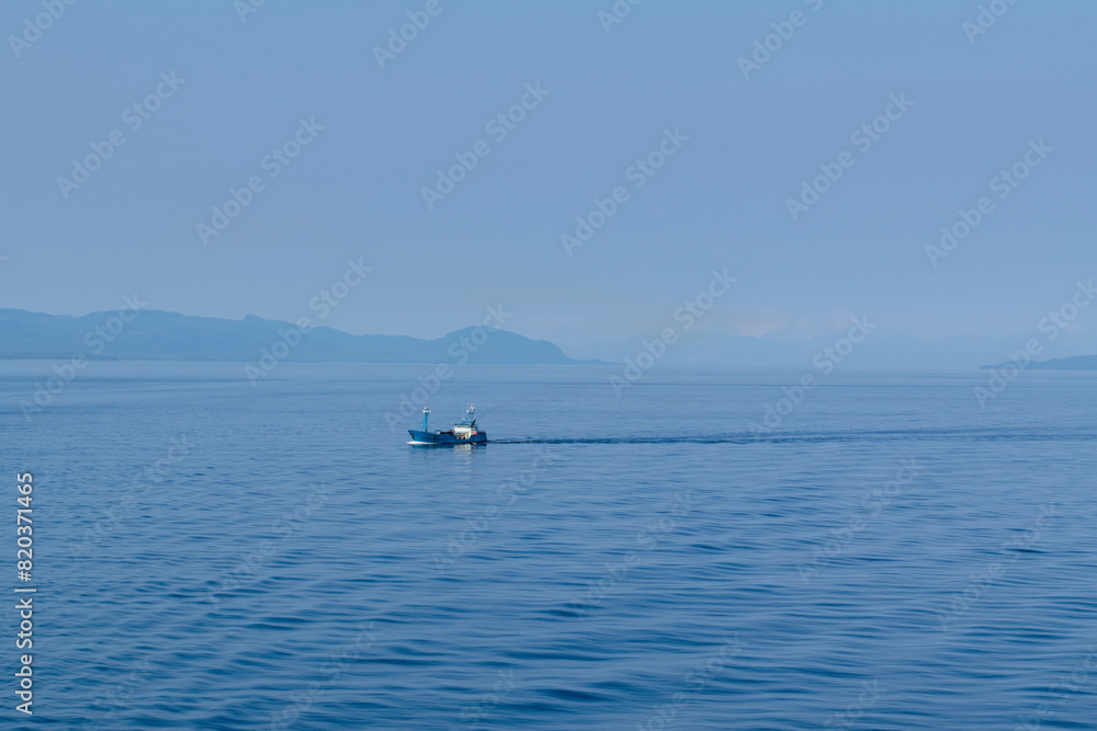 Panoramic view of the Alaskan mountain range on a summer day in August. A trawler is visible in the foreground. Panoramic view of the Alaskan mountain range on a summer day in August. A trawler is visible in the foreground.