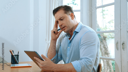 Photography Businessman struggle to solve work problem from home using laptop, sitting on his desk at home office with stressed and frustrated expression, trying to figure out solution for problem