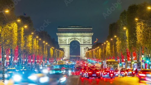 4K Timelapse of traffic at Arc de Triomph at night. This historical monument overlooks the avenue des champs élysées in the heart of Paris, French capital. photo
