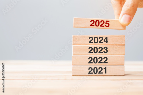 2025 block over 2024 and 2023 wooden building on table background. Business planning, Risk Management, Resolution, strategy, solution, goal, New Year New You and happy holiday concepts