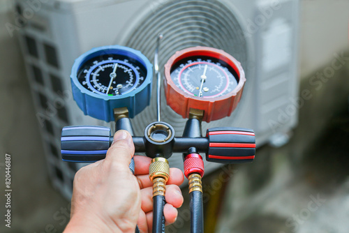 Air conditioning, HVAC service technician using gauges to check refrigerant and add refrigerant. 