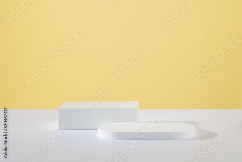 Minimal scene concept with two podiums in different geometric shapes featured over yellow background. Pastel minimal wall scene collection. Modern platform for product display presentation