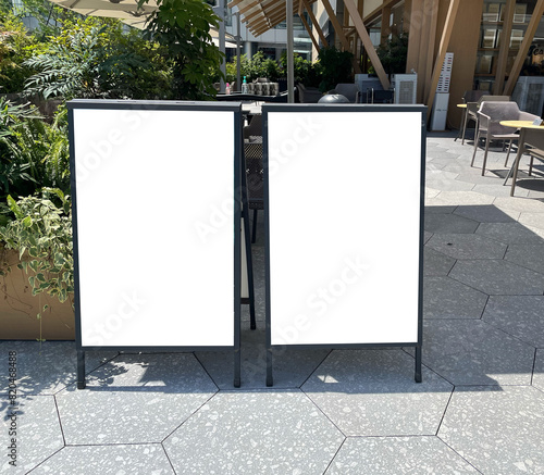 Mockup of the blank white street city outdoor advertising vertical poster sign stand on restaurant entrance sidewalk. photo