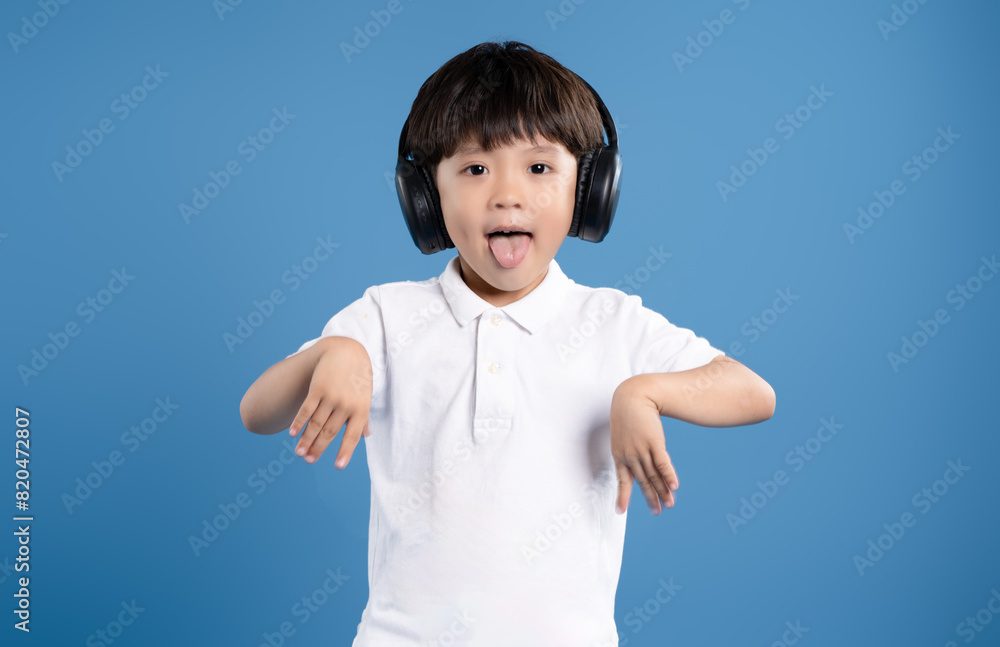 Portrait of asian boy wearing headphones and posing on blue background Portrait of asian boy wearing headphones and posing on blue background