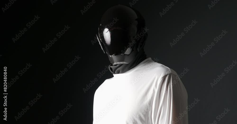 Unrecognizable man in black robot mask, looking around. Unrecognizable man in black robot mask, looking around.
