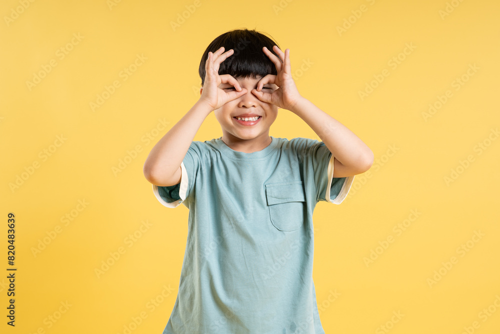 Portrait of adorable asian boy posing on yellow background Portrait of adorable asian boy posing on yellow background