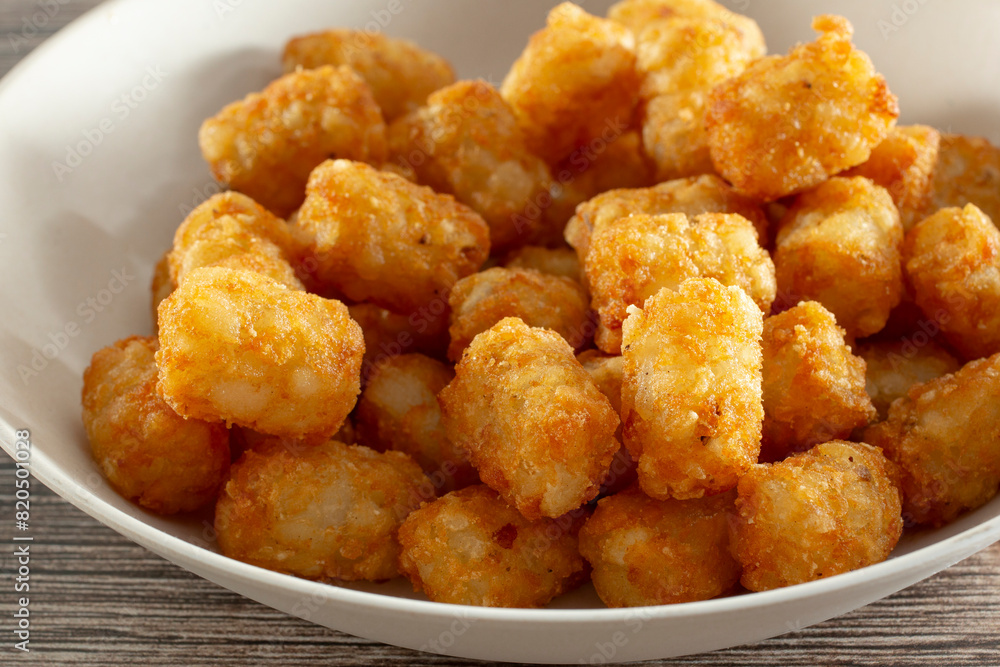 A closeup view of a bowl of deep fried tater tots. A closeup view of a bowl of deep fried tater tots.