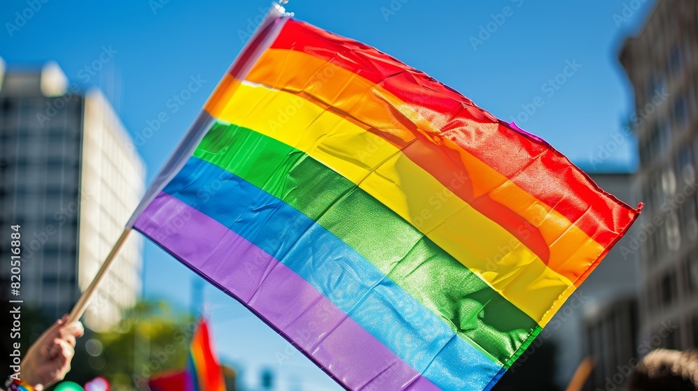 LGBTQ pride flag flying in an urban setting, ideal for promoting diversity, inclusion, and LGBTQ rights in city-focused advertising and social media posts. LGBTQ pride flag flying in an urban setting, ideal for promoting diversity, inclusion, and LGBTQ rights in city-focused advertising and social media posts.