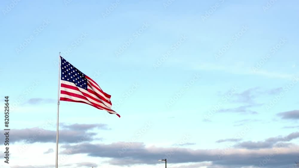 The American flag waves proudly against a backdrop of a softly clouded sky, symbolizing patriotism and national pride in a serene setting The American flag waves proudly against a backdrop of a softly clouded sky, symbolizing patriotism and national pride in a serene setting
