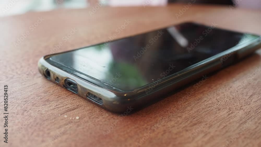 A hand grabbing and picking up mobile phone on the table. A hand grabbing and picking up mobile phone on the table.