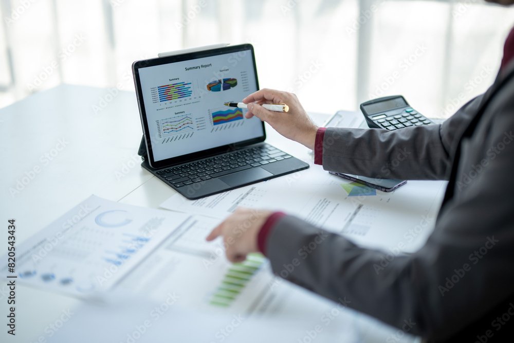 A person is working on a laptop with a tablet and a calculator on a table A person is working on a laptop with a tablet and a calculator on a table