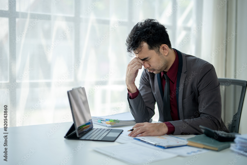 A man is sitting at a desk with a laptop and a tablet A man is sitting at a desk with a laptop and a tablet