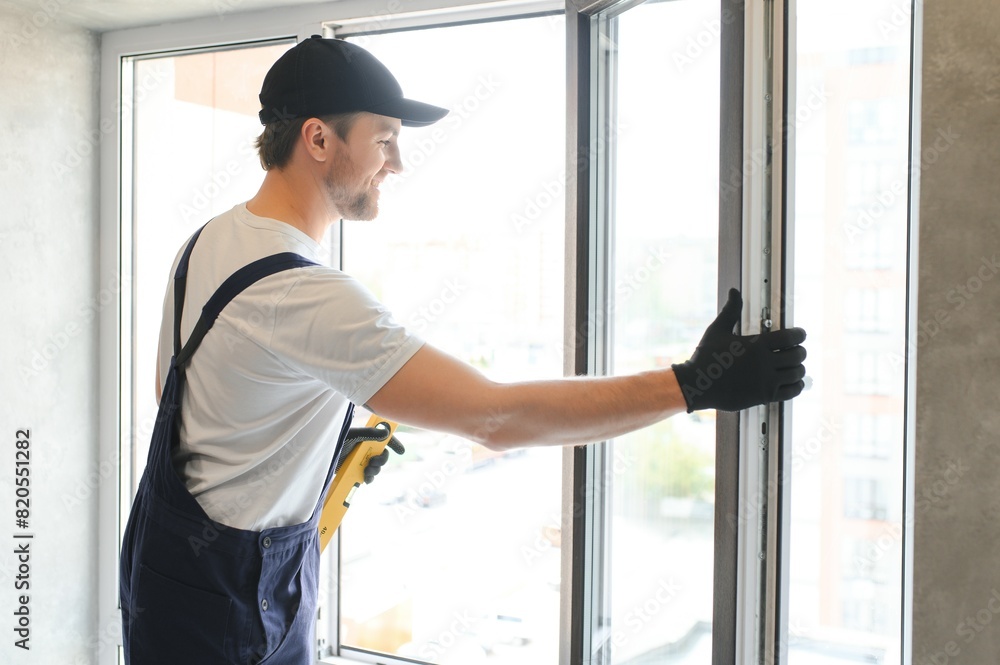 The foreman installs a window frame in the room The foreman installs a window frame in the room