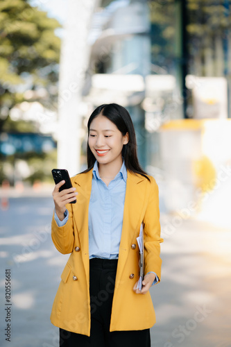 Young Asian business woman leader entrepreneur, professional manager holding digital tablet computer uon the street in big city photo