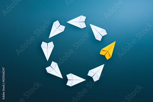 Group of white paper planes float in a circular direction and one yellow paper plane pointing in different way. Business for new ideas creativity, innovative and solution concept.