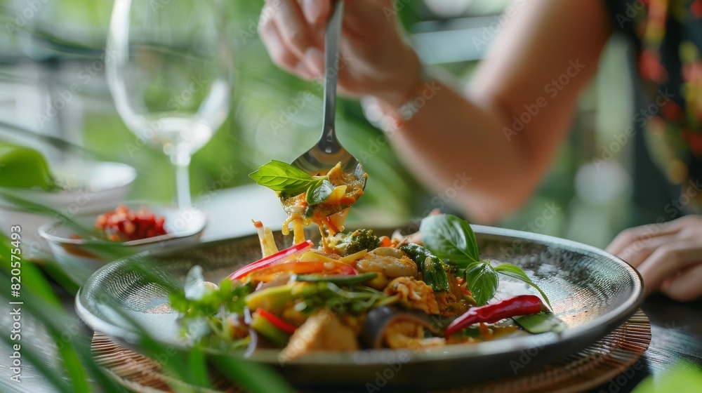 Hand serving a portion of authentic Thai curry from a stylish plate, capturing the vibrant colors and aromatic spices, ideal for a business setting Hand serving a portion of authentic Thai curry from a stylish plate, capturing the vibrant colors and aromatic spices, ideal for a business setting