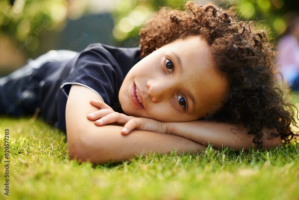 Portrait, boy child and lying on grass in outdoor park for chilling, comfort and relax in nature. Happiness, holiday and young kid on lawn for childhood, weekend break or family trip in Monaco Portrait, boy child and lying on grass in outdoor park for chilling, comfort and relax in nature. Happiness, holiday and young kid on lawn for childhood, weekend break or family trip in Monaco