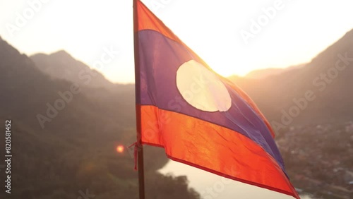 Laos flag flapping in the wind at sunset in the mountain town of Nong Khiaw in Laos, Southeast Asia photo