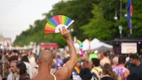 Bald gay man raise hand up above crowd. Bi guy hold colorful rainbow fan. Fun lgbt party fest. No stop homophobia. Pride month celebration. Joyful csd day. Free person coming out. Love parade symbol. photo