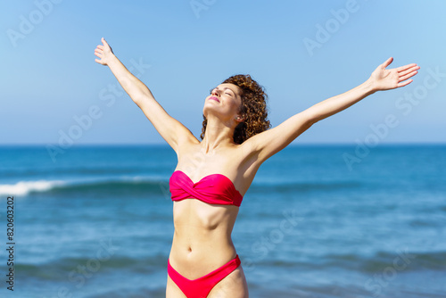 Cheerful slim woman in bikini with raised arms