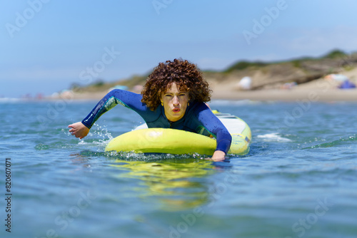 Focused woman on paddleboard rowing with hands in sea
