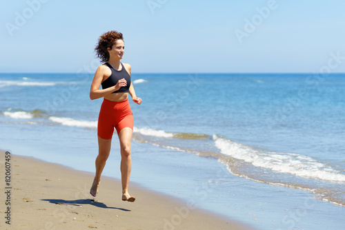 Happy young woman training on sandy beach and running