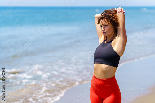 Pensive woman stretching on seashore