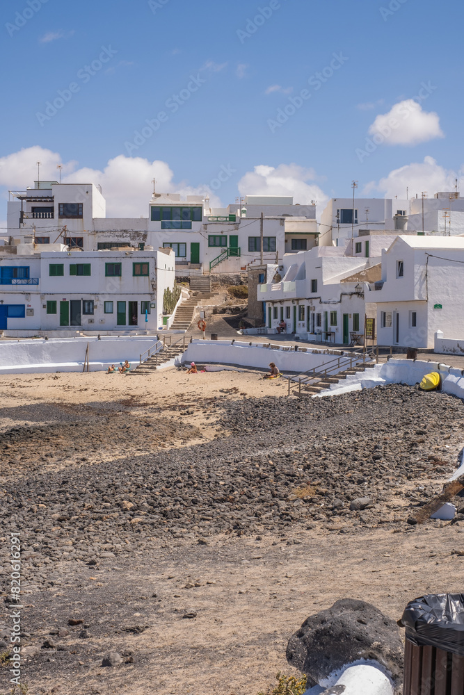 Fototapeta premium Typical white houses of the village of Caleta de Caballo. Dirt street and boats on the ground. Lanzarote, Canary Islands, Spain