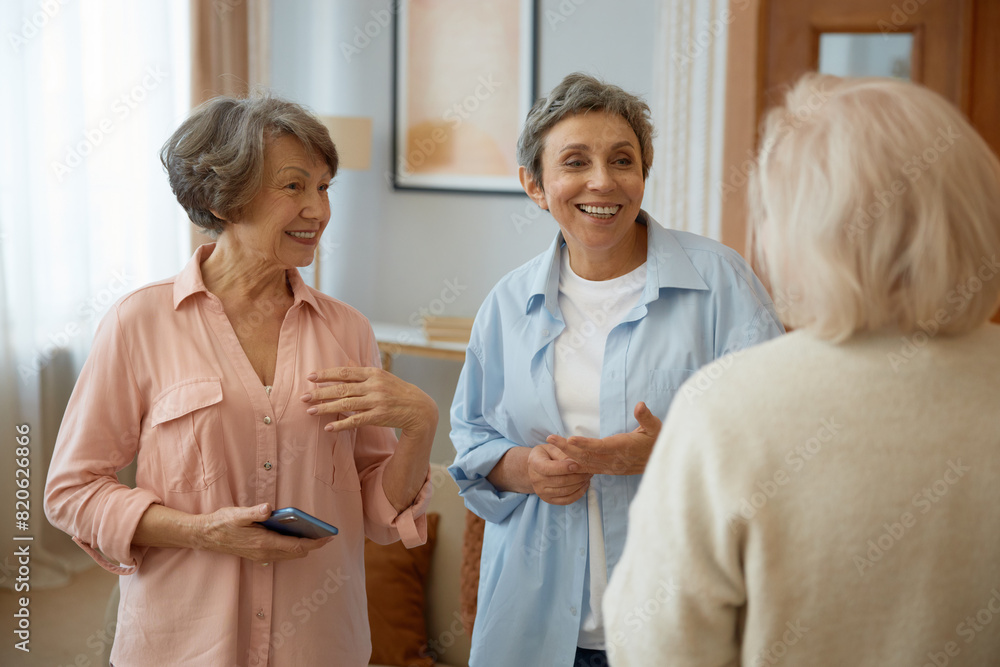 Fototapeta premium Elderly women friends laughing at home living room